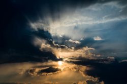 A stunning sunset with sunbeams shining through dark clouds, creating a dramatic sky scene.